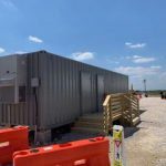 A large gray container sitting next to orange construction cones.