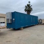 A large blue container sitting in the middle of a parking lot.