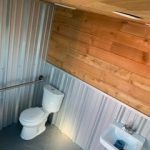 Small bathroom with white fixtures and mixed wooden paneling.