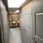 A hallway with two doors and three sinks.