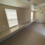 A room with two windows and a bench in it.